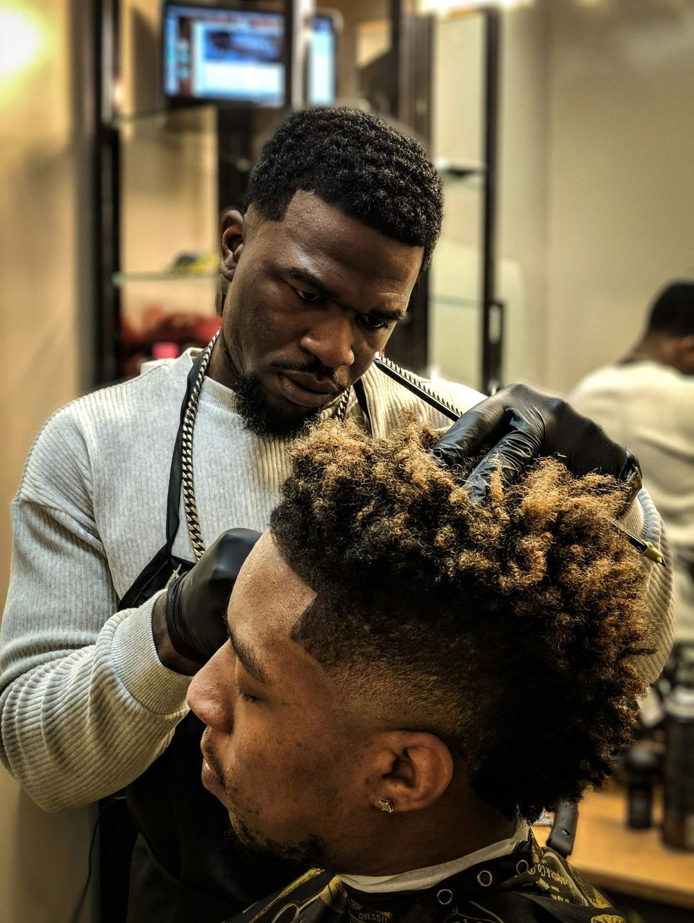 A barber shaping a client's fade